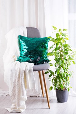White plaid and green sequins pillow with flower pot on gray armchair over window of living room